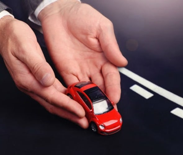 AAA insurance policy holder's hands placing a red toy car on a road.