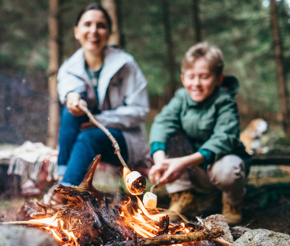Mother and son roast marshmallows over the campfire.