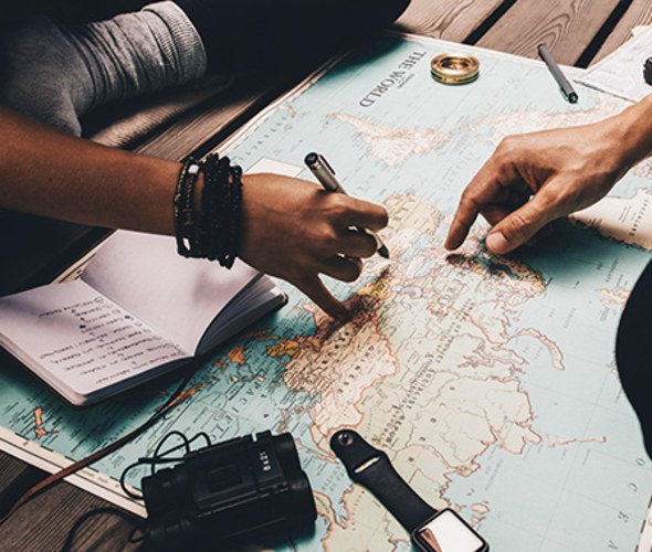 friends plan a trip with AAA travel resources and a map of the world