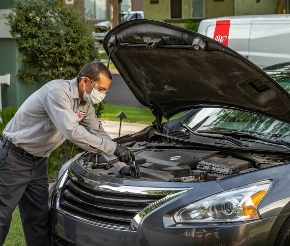 AAA mobile auto repair technician performs a car diagnostic test in a customer's driveway