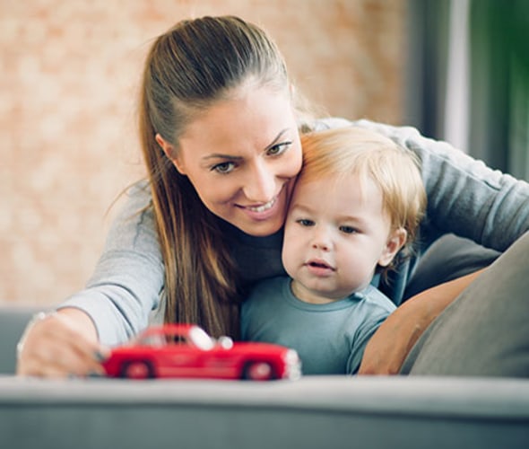 a mom with AAA life insurance plays on the couch with her toddler son