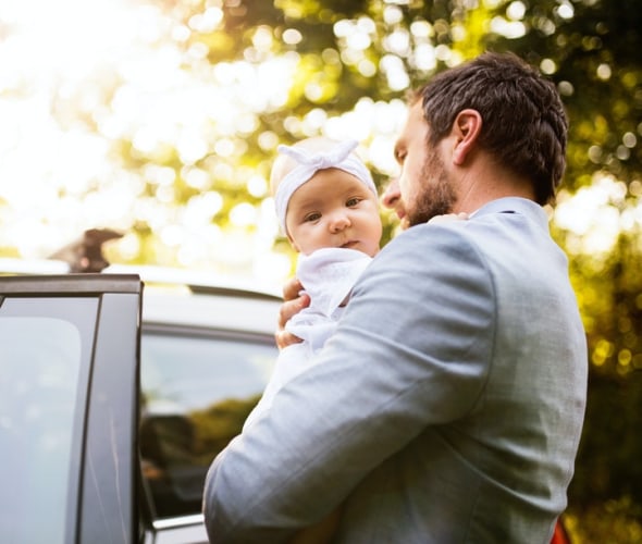 a caregiver walks a baby to a car