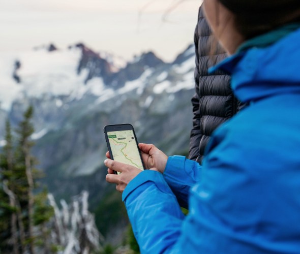 A woman uses Gaia GPS when hiking in the spring.