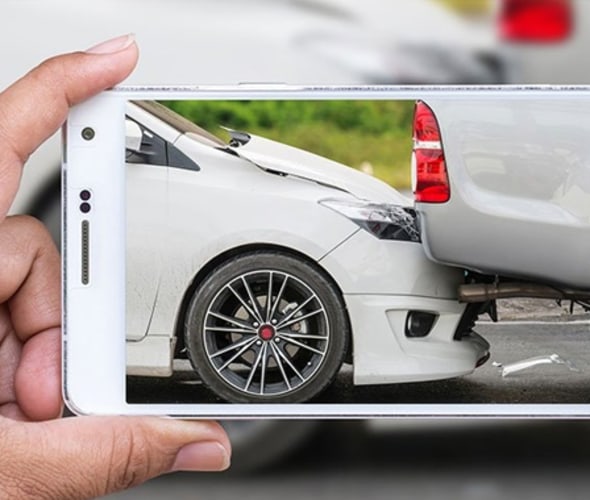 AAA member taking a picture on a cell phone of a car that rear-ended another vehicle