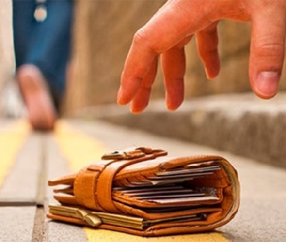 a person picks up a wallet from the ground