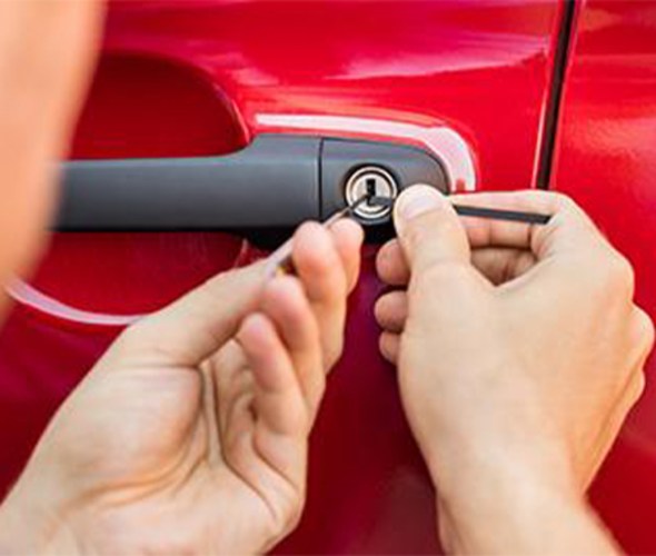 a man uses a lock pick to get into a red car door