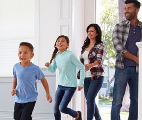 mother, father and two children walking through the front door of their home covered by aaa homeowners insurance