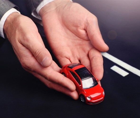 Hands representing a AAA auto insurance agent gently placing a car on the road