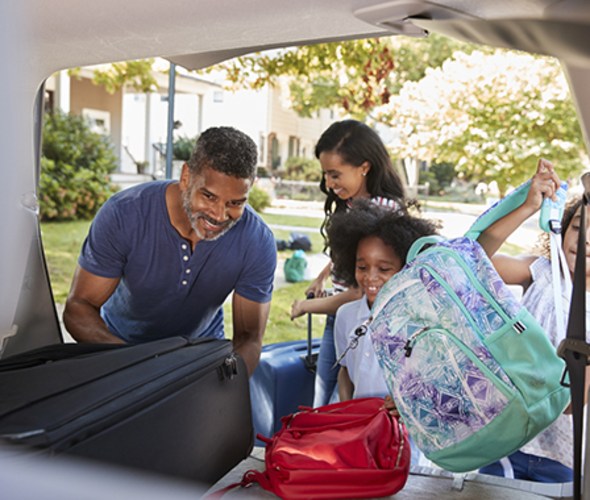 family placing luggage in dollar rental car