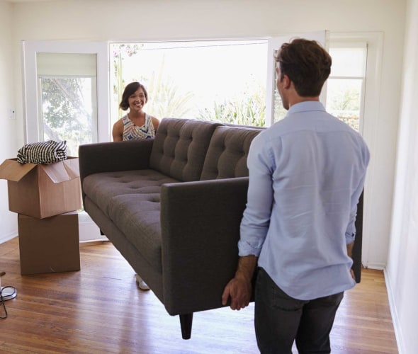 Couple moving a couch into their into first apartment