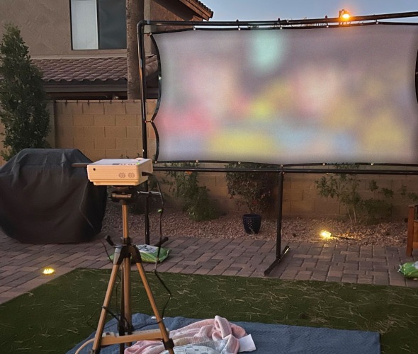 A projector plays a movie on a DIY projector screen.