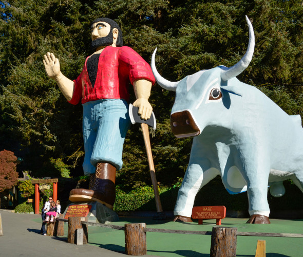 Paul Bunyan waves and leans on his ax beside Babe the Blue Ox, in Klamath, California