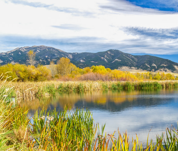 A beautiful reservoir in autumn fields at the foot of the Bridger mountain range in Cherry Creek Nature Preserve.