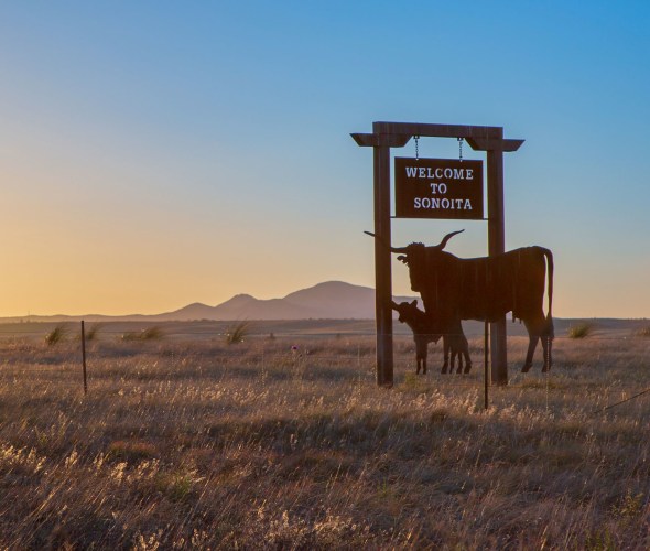 pair of steel longhorns welcomes travelers to Sonoita, Arizona, as sun sets in the background