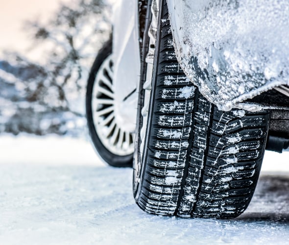 Tire with snow in the treads on a snow-covered road.