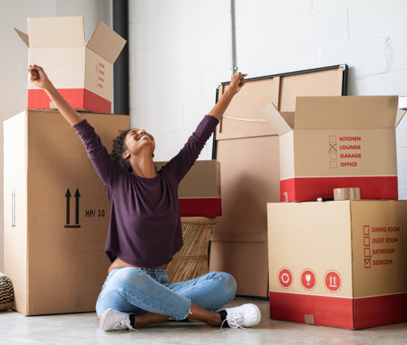 A woman sits in front of boxes in her new apartment.