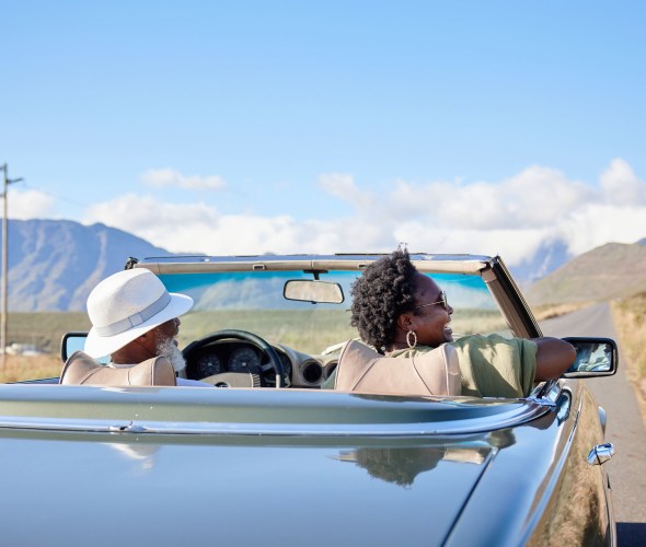 A couple drive in a vintage convertible.