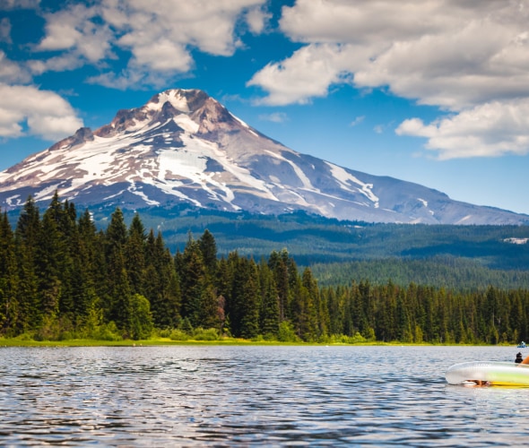 A woman floats on Lake Trillium in Oregon with Mount Hood in the background.