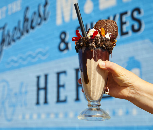 A glass of the The Dirt Stack milkshake, which is a vanilla shake in a chocolate syurp lined glass, topped with oreo crumble, gummy worms and a hostess cupcake, from Danzeisen Dairy Creamery Store.