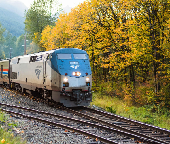 An eastbound Amtrak Empire Builder train passes through the Cascade Mountains near Skykomish, Washington as the trees turn fall colors.