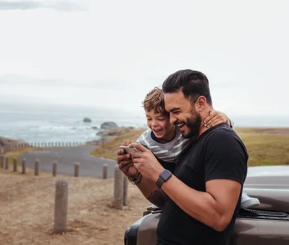 Man and boy looking at phone on the coast