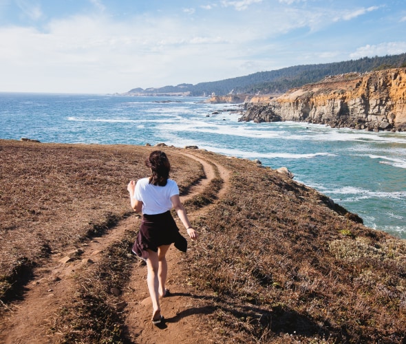 a woman walks on the bluff at California's Salt Point State Park.