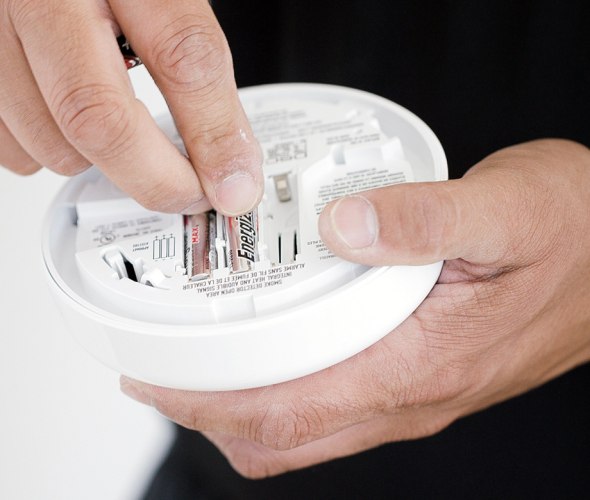 Person changing batteries in smoke alarm
