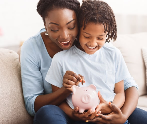 Mother and daughter putting money into a piggy bank