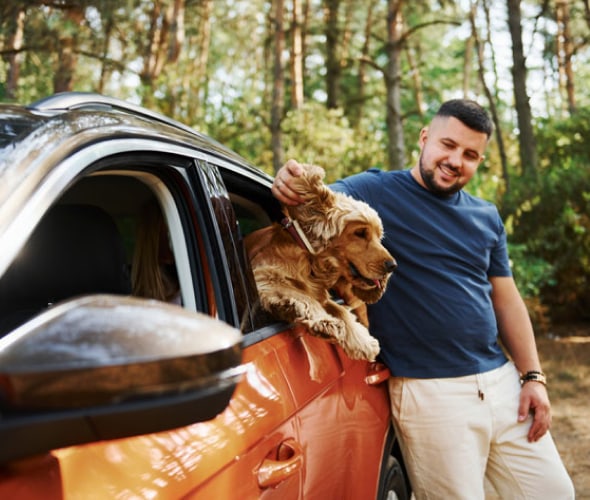 Man standing outside of car petting dog