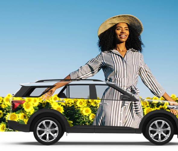 Woman standing by rental car near flowers