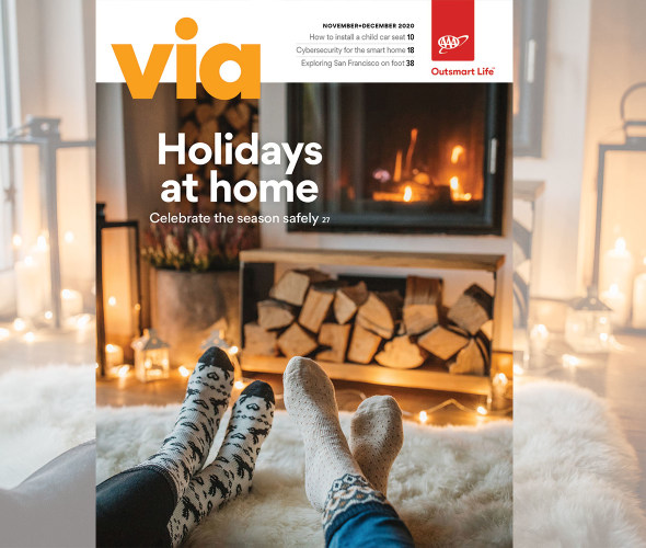AAA Members sitting in front of a fireplace in winter on the cover of Via magazine's November December 2020 issue.