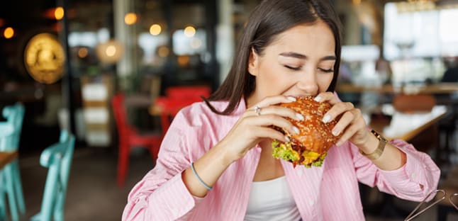 AAA Member takes a bite out of their burger ordered using AAA discounts