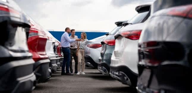 A hand adjusts the dash of a car after finding a car with the auto buying program