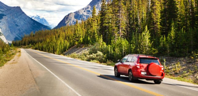 Member drives a road through the mountains in a rental car