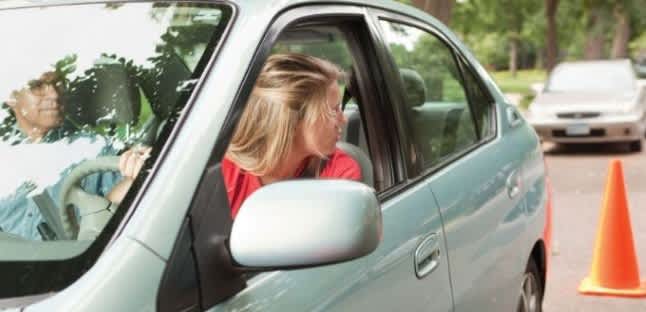 a teen driver looks over their shoulder as they back up