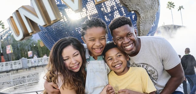 Family smiling in front of Universal Orlando Resort globe sign 