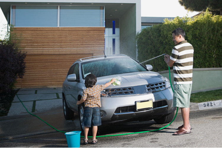 Father and son washing car in driveway