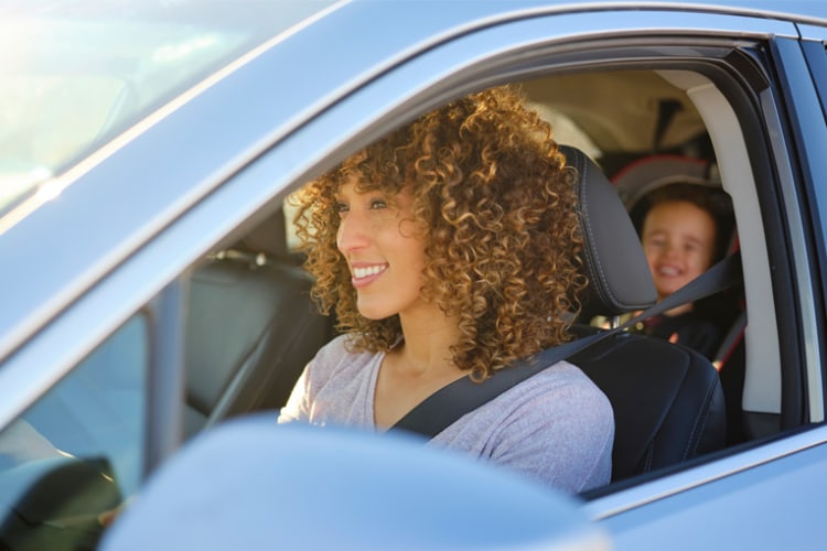 Woman driving with kid in backseat