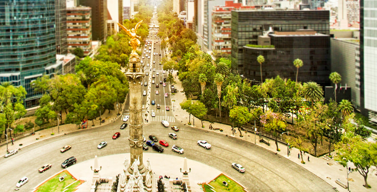 Cars with AAA Mexico Insurance drive around El Angel, Angel of Independence, in Mexico City