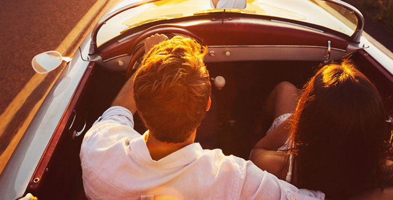 A couple drives a convertible covered with AAA car insurance 