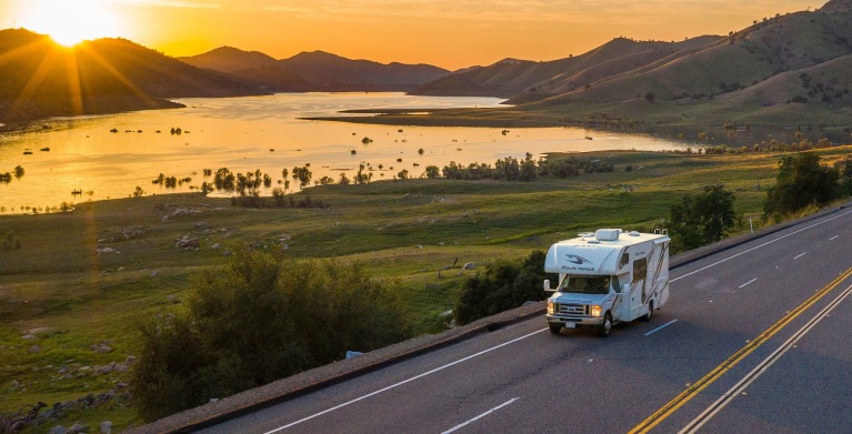AAA Members drive an RV on the highway at sunset.