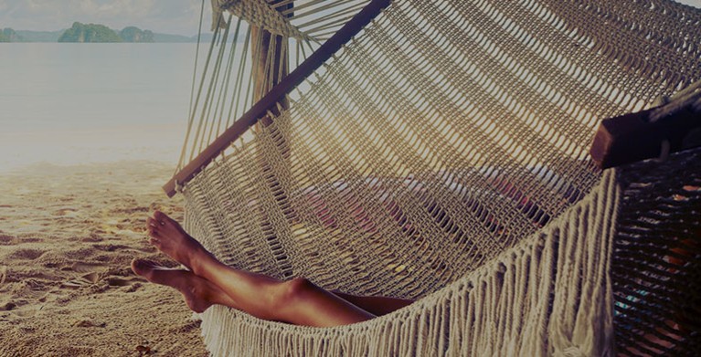 A AAA Member with auto renew membership relaxes in a hammock at the beach on vacation