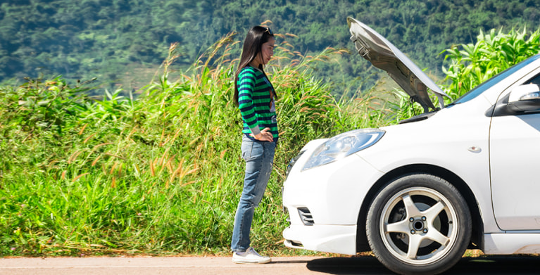 AAA Member looking under the hood of her car to check her car battery.