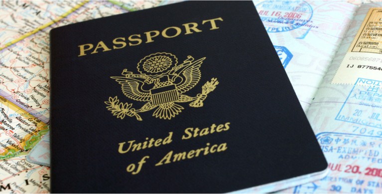 US passport cover and interior page on top of a map