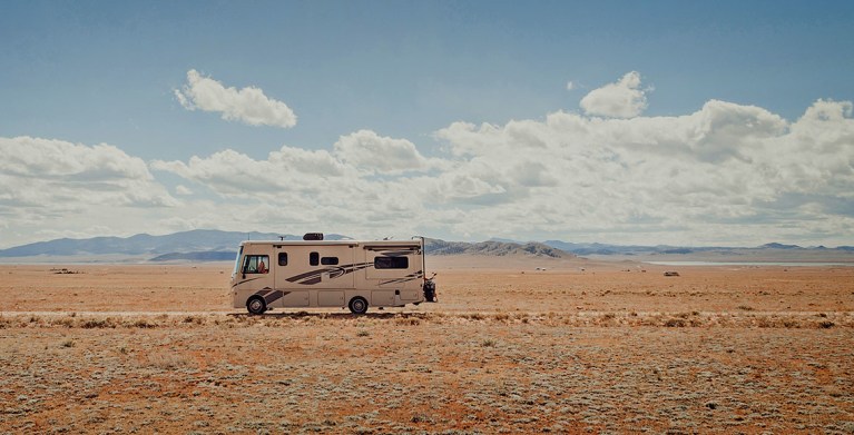 RV insured by AAA on the road in the desert under a cloudy sky