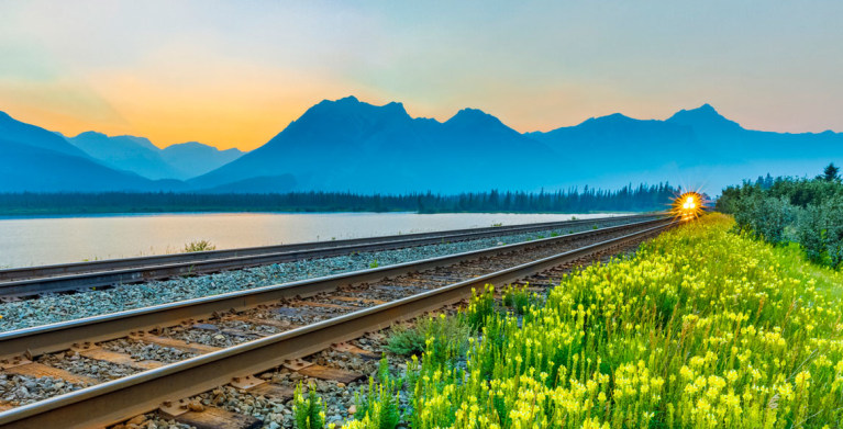 train on tracks near lake in jasper national park