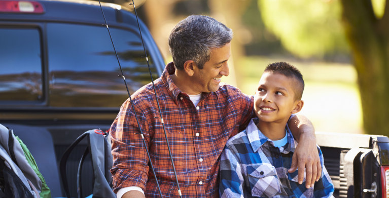 Father with AAA Express term life insurance sites in a truck bed with his son