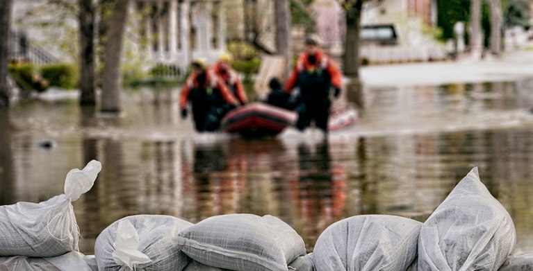 men wading flood waters to reach a home with AAA flood insurance