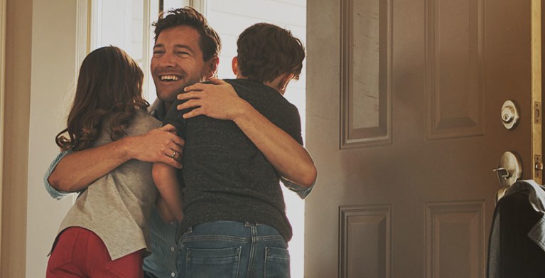 children greeting their father at the door of their home protected by AAA homeowners insurance.