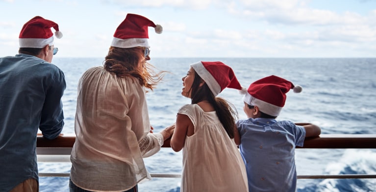 family wearing santa hats on deck of ship on holiday cruise
